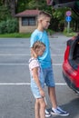 Girl is standing interestedly next to her brother by the trunk of a red car Royalty Free Stock Photo