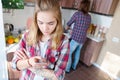 A girl is standing in the kitchen with a phone in her hands and is scamming a message surfing the Internet ordering food