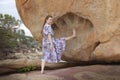 The girl is standing near a large stone, with a giant& x27;s footprint