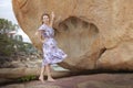 The girl is standing near a large stone, with a giant& x27;s footprint