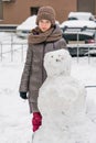 Girl standing next to a snowman in winter