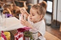 Girl standing at the table and holding glass with paints while making drawings at the art school Royalty Free Stock Photo