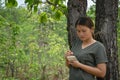 The girl is standing, taking notes in a small note book in the green forest