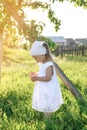 A girl standing under an apple tree in the sunlight. Barefoot baby in the garden