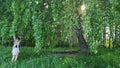 The girl is standing under a birch tree.