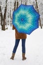 Girl standing under blue umbrella in snowy forest . Snowfall concept. Woman under wet snow rain in winter park. Royalty Free Stock Photo