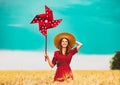 Girl is standing on a wheat field with pinwheel Royalty Free Stock Photo