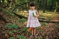 Girl standing in the woods holding a toy bear in hand