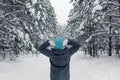 a girl stands in a beautiful winter snowy forest, raising her hands to her head, examines the trees. Royalty Free Stock Photo