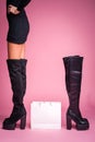 The girl stands in Black jackboots on her feet on a pink background. In the middle there is a bag from the store. There is another Royalty Free Stock Photo