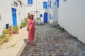 Girl stands in the courtyard with blue windows and doors with Arabic ornaments. Texture of Islamic symbols in Sidi Bou said, Royalty Free Stock Photo