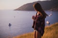 A girl stands on the edge of the cliff near the sea or ocean and looking at the sun valley. Woman enjoying a sunset or Royalty Free Stock Photo