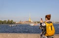 Girl stands on the embankment against the background of the Peter and Paul fortress in St. Petersburg, Neva