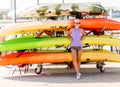 Girl stanfs in front of a pile of kayaks and canoes ready to sail in the sea. Royalty Free Stock Photo