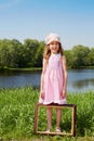 Girl stands on bank of pond, picture frame is at her feet Royalty Free Stock Photo