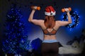 Girl stands with his back in sports leggings and a top. Woman bodybuilder holds dumbbells against the background of the