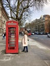 A girl stands near the famous red London telephone box on a busy street UK London