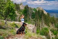 Girl with stands next to her dog of the Rottweiler breed on a peak with vegetation against the cloudy sky Royalty Free Stock Photo