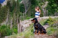 Girl with stands next to her dog of the Rottweiler breed on a peak with vegetation against the cloudy sky Royalty Free Stock Photo