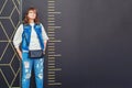 Girl stands next to a large scale ruler. Measurement of a woman in full growth. Man in denim near the wall with divisions/ Copy