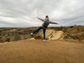 The girl stands on one leg on top of a mountain and spread her arms. Symbol of freedom and success. View of the valley. Cappadocia