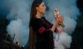 Girl stands with owl on her hand in forest against smoke background. Royalty Free Stock Photo