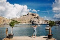 A girl stands on the pier of St. Paul`s Bay and the Acropolis in Lindos, Rhodes, Greece Royalty Free Stock Photo