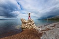 The girl stands on a pile of stones and looks at the sea