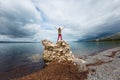 The girl stands on a pile of stones and looks at the sea