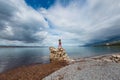 The girl stands on a pile of stones and looks at the sea