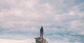 The girl stands on a pile of stones and looks at the sea