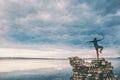 The girl stands on a pile of stones and looks at the sea