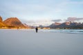 Girl stands on Ramberg beach in Lofoten in Norway during sunset.
