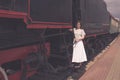 A girl stands on the steps of the cars train. The vintage train is at the station. Embarkation or disembarkation of the passenger Royalty Free Stock Photo