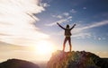 The girl stands on top of the mountain and enjoys the view of the valley.