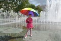 The girl stands under an iridescent umbrella near the fountain. Kaliningrad Royalty Free Stock Photo