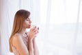 Girl stands at the window with a mug Royalty Free Stock Photo