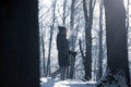 A girl stands in a winter forest on a frosty day. Blue tint