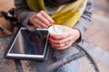 Girl stiring her coffee in the park. Tablet pc on the table. Close up. Royalty Free Stock Photo