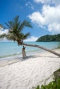 The girl stood back, standing under a coconut tree with bent trunks