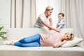 Girl stopping father from awaking pregnant woman that sleeping on sofa