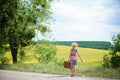 Girl in straw hat with retro suitcase near summer