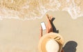 A girl in a straw hat sits on the beach with a phone in her hand. Royalty Free Stock Photo