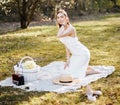 Girl with a straw hat in the spring in the park. Brunette with long hair sitting on a plaid on a background of summer nature. Royalty Free Stock Photo