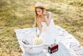 Girl with a straw hat in the spring in the park. Brunette with long hair sitting on a plaid on a background of summer nature. Royalty Free Stock Photo