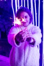 The girl is holding sparklers in her hands on a background of pink lights Royalty Free Stock Photo