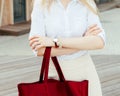 Girl on the street with a big red super fashionable handbag in a White blouse and skirt on a warm evening. Outdoor.