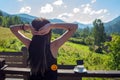 The girl stretches, looking at the morning sun and mountains. Next to her, on the railing of the balcony, is a cup of coffee Royalty Free Stock Photo