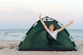 Girl stretches in the morning in tent. Camping by the sea. Traveling, hiking