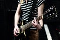 A girl in a striped shirt with an electric guitar stands on the recording Studio. The guitarist plays the strings of a musical Royalty Free Stock Photo